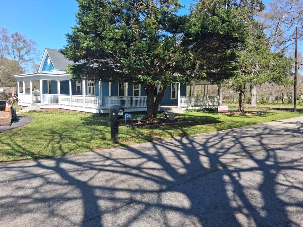 Blue farmhouse with a well-maintained, freshly mowed lawn